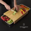 Hands are shown chopping vegetables on a wooden cutting board with integrated stainless steel trays. Produktbild-Vorschau