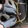A person wearing gloves is installing snow chains on a car tire. Produktbild-Vorschau