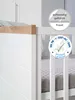 Close-up of a white crib with a wooden trim and certification badges. Produktbild-Vorschau