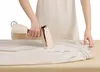 A person is using a handheld steamer to iron a pair of light-colored pants. Produktbild-Vorschau