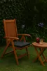 A wooden chair and side table with drinks on it, set in a garden. Produktbild-Vorschau