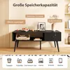 A black coffee table with storage is shown in a living room setting, with text overlays highlighting its features and icons at the bottom indicating storage possibilities. Produktbild-Vorschau