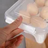 A hand is holding the latch of a clear plastic egg container filled with eggs. Podgląd zdjęcia produktu