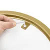 A close-up of a hand using a hex wrench to tighten a screw on a gold-colored metal frame. Produktbild-Vorschau