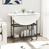 A white marble-look folding dining table with black metal legs and shelves, set up in a living room next to a white sofa. Podgląd zdjęcia produktu