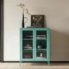 A teal metal cabinet with glass doors is displayed against a light gray wall. Produktbild-Vorschau