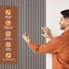 A man is shown installing a wooden slat wall panel. The image includes icons and text describing the product's features. Náhľad obrázku produktu