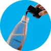 A hand is pouring a brown liquid from a black adapter into a clear Sodastream bottle filled with water. Produktbild-Vorschau