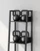 A set of black kettlebells on a black shelf unit. Náhled obrázku produktu