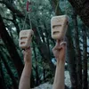 Zwei Klettergriffe des Produkts "Rocky" von YY Vertical; hängen an einem Baum. Eine Hand greift nach dem rechten Griff. Podgląd zdjęcia produktu