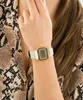A close-up shot of a person's wrist wearing a gold digital watch with a white band. Voir les images du produit