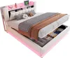 A white upholstered bed with storage drawers open, showing folded items inside. The bed has a headboard with shelves and LED lighting. Produktbild-Vorschau