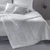 A white duvet is laid out on a bed with pillows. Produktbild-Vorschau