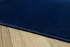 A close-up view of a dark blue rug on a wooden floor. Produktbild-Vorschau