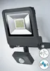 A dark gray LED floodlight with a motion sensor attached, mounted on a light gray wall. Produktbild-Vorschau