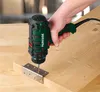 A person is using a cordless drill to attach a metal hinge to a wooden surface. Produktbild-Vorschau