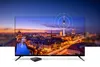 A television displaying a cityscape at dusk, with a small black box device in front of it. Produktbild-Vorschau