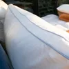 A close-up view of a white pillow with a blue stitched seam, with other pillows in the background. Produktbild-Vorschau