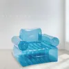 A transparent blue inflatable armchair is shown in a well-lit room with a white wall and light wooden floor. Produktbild-Vorschau