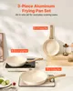 A set of three aluminum frying pans with wooden handles, displayed on a table with some fruit and kitchen accessories. Náhľad obrázku produktu