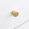 A close-up shot of a single gold-colored drawer knob on a white surface. Podgląd zdjęcia produktu