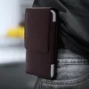A close-up shot of a brown leather belt pouch attached to a person's jeans. Náhled obrázku produktu