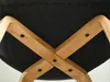 Close-up view of the underside of a chair, showing the wooden frame and black upholstery. Voir les images du produit