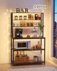 A coffee bar setup on a tiered shelf unit, complete with a coffee maker, microwave, various coffee bags, bottles, and decorative items. Fairy lights are strung around the unit. Náhled obrázku produktu