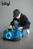 A young boy in a black hoodie and baseball cap is kneeling and zipping up a blue and green sports bag with a soccer ball design. Náhľad obrázku produktu