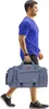 A man walks while carrying a large duffel bag. Produktbild-Vorschau