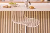 A transparent bar stool is shown in a kitchen setting with a counter and some breakfast items. Produktbild-Vorschau