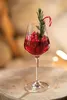 A festive drink in a wine glass, garnished with berries, rosemary, and a candy cane. Náhľad obrázku produktu