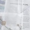 A close-up view of a sheer curtain with embroidered flowers and text printed on it. Produktbild-Vorschau