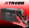 A black battery charger with red and black clamps is shown against a red and black gradient background. The brand logo is prominently displayed at the top. Náhled obrázku produktu