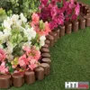A garden border made of brown plastic logs, separating artificial grass from artificial flowers. Produktbild-Vorschau