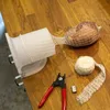 A piece of meat wrapped in netting, with tools for preparing it, laid out on a wooden table. Produktbild-Vorschau