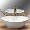A marble-patterned vessel sink with a gold faucet is shown in front of a mirror. Produktbild-Vorschau