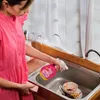 A person is cleaning dishes in a kitchen sink. Produktbild-Vorschau