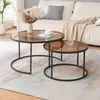 Two round coffee tables with brown glass tops and black metal frames are placed on a rug in front of a sofa. Náhľad obrázku produktu