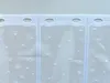 A close-up view of a white sheer curtain with a polka dot pattern and grommets at the top. Produktbild-Vorschau