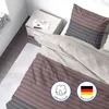 A neatly made bed with striped bedding and a pillow, next to a nightstand with a magazine and a cup. Produktbild-Vorschau