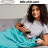 A woman is relaxing on a sofa, covered with a turquoise blanket, holding a glass of red wine and a remote control. Produktbild-Vorschau