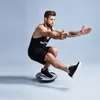 A man is performing a single-leg squat on a balance board. Produktbild-Vorschau