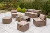 A patio set with a sofa, chairs, ottomans, and a coffee table arranged on a tiled patio with greenery in the background. Produktbild-Vorschau