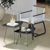 A set of two black nesting tables with a chair and decorative items on a patio. Anteprima dell’immagine prodotto