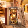 A miniature diorama of a Japanese alleyway, resembling a book nook, is placed between several books on a shelf. Náhled obrázku produktu