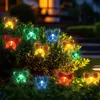 Colorful butterfly-shaped solar lights are illuminating a bush at night. Produktbild-Vorschau