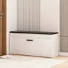 A white shoe cabinet with a black top is shown in a hallway next to a wooden door and a patterned wall. Podgląd zdjęcia produktu