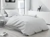 A neatly made bed with white bedding in a bright, modern room. Náhled obrázku produktu