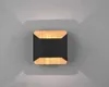A modern wall lamp with a black center and wood-toned frame, mounted on a gray wall, casting light upwards and downwards. Podgląd zdjęcia produktu